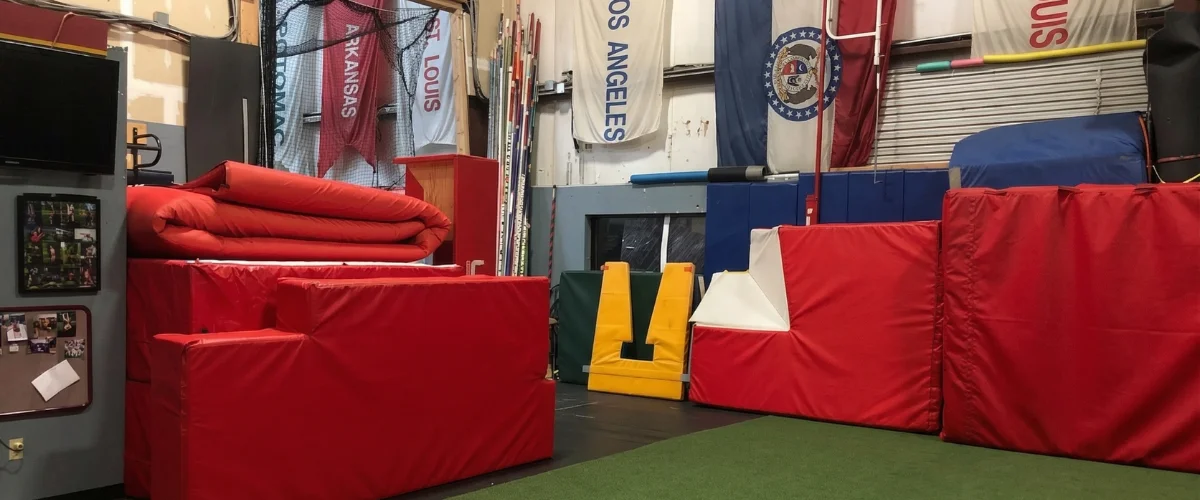 Bright red and yellow gymnastics mats and other soft equipment in what appears to be a training gym.