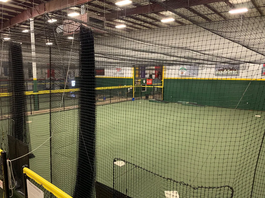 Indoor baseball and softball batting cages with nets and turf lanes at training facility