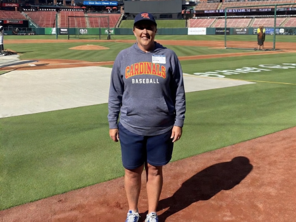Instructor standing on a baseball field in Cardinals apparel during a training session
