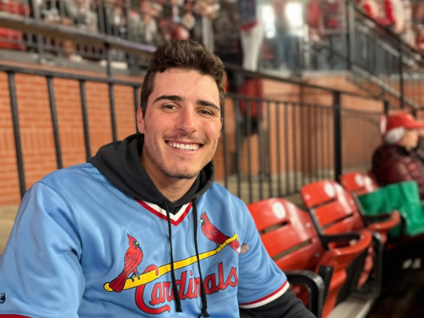 Smiling instructor wearing a Cardinals jacket sitting in stadium seats