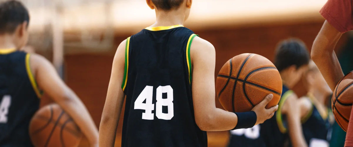 A young basketball player in a black jersey with number 48 on the back, holding a basketball on court. A young basketball player in a black jersey with number 48 on the back, holding a basketball on court.