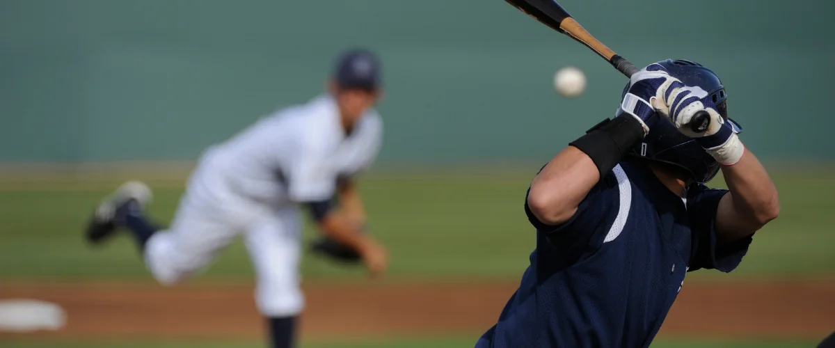A baseball batter in a white jersey with number 6 hitting a baseball, with a catcher in a blue jersey in the foreground. A baseball batter in a white jersey with number 6 hitting a baseball, with a catcher in a blue jersey in the foreground.