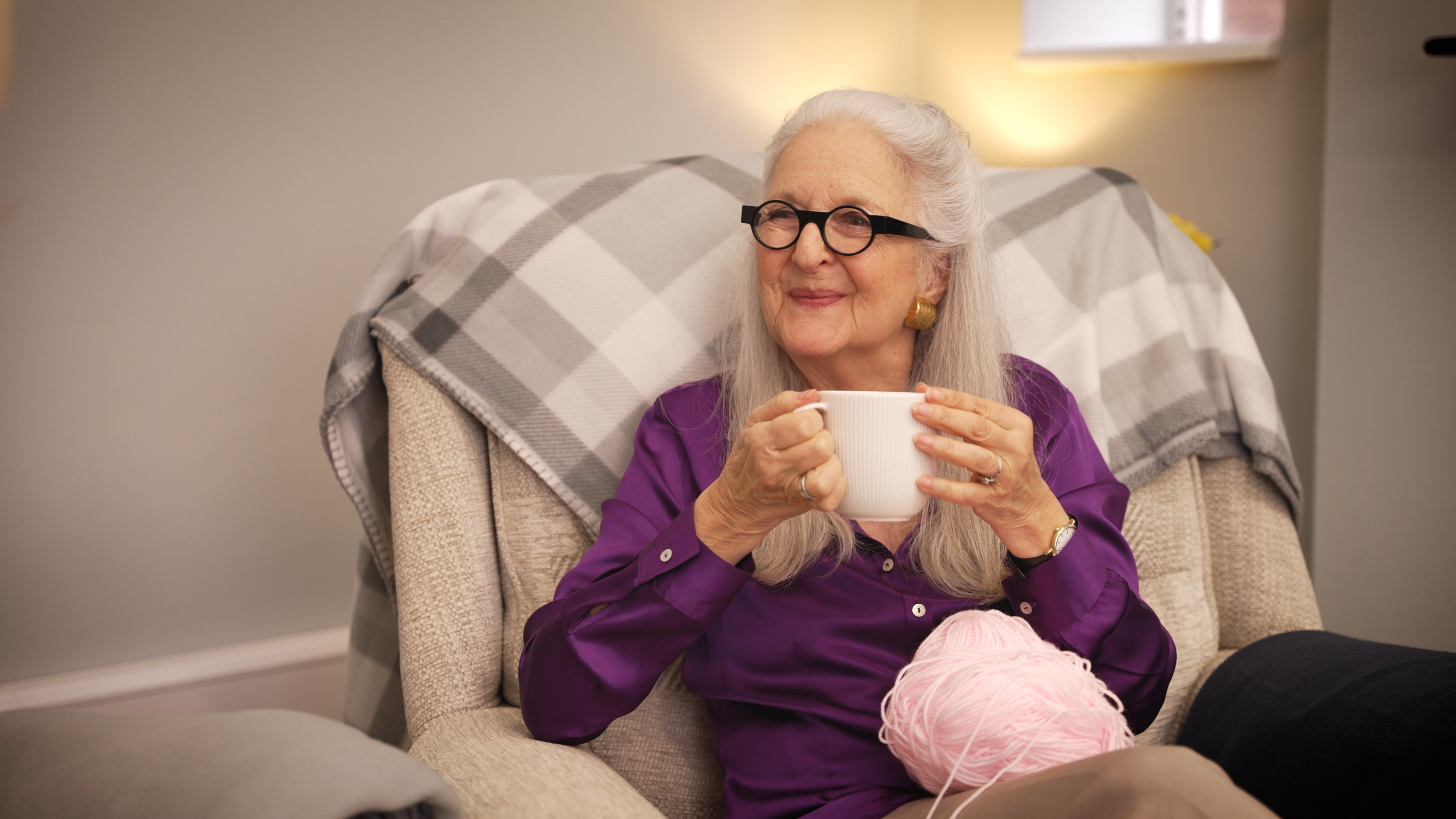 An older woman enjoying a cup of tea at home