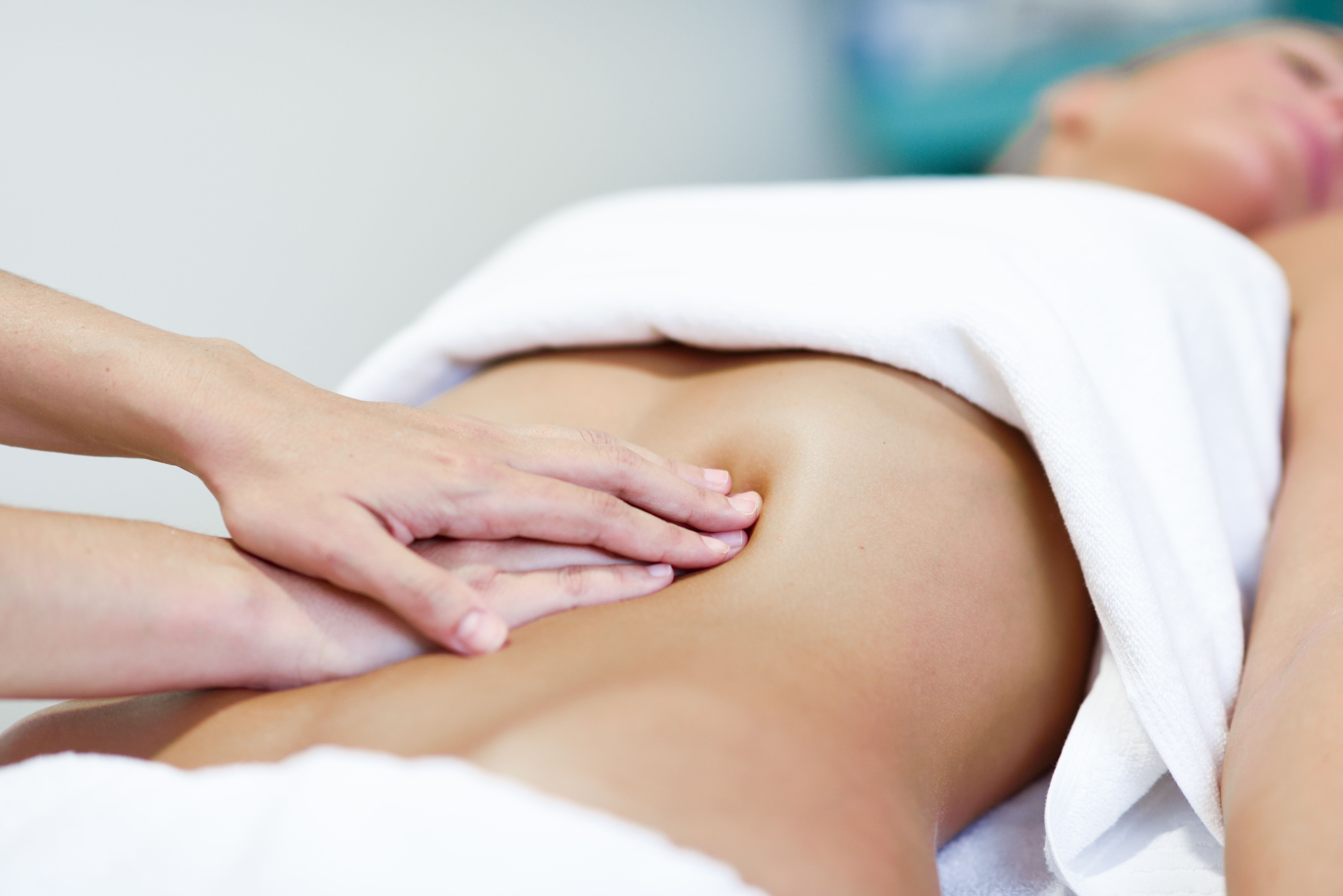 Therapist performing gentle clinical lymphatic drainage on a client’s arm in warm neutral surroundings