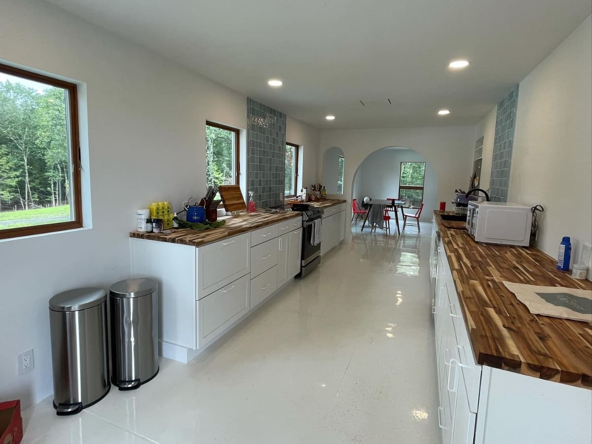 Modern kitchen with white cabinetry, butcher block countertops, stainless steel appliances, and a bright dining area in a newly built home in Catskill.