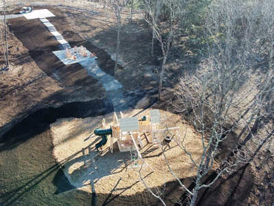 Aerial view of a septic system installation site, with septic suction equipment being used in snowy conditions near a residential property in Leeds