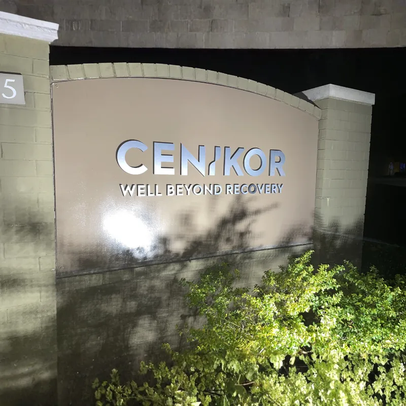 Monument sign for Cenikor with brick pillars and address plaque at a DFW commercial property