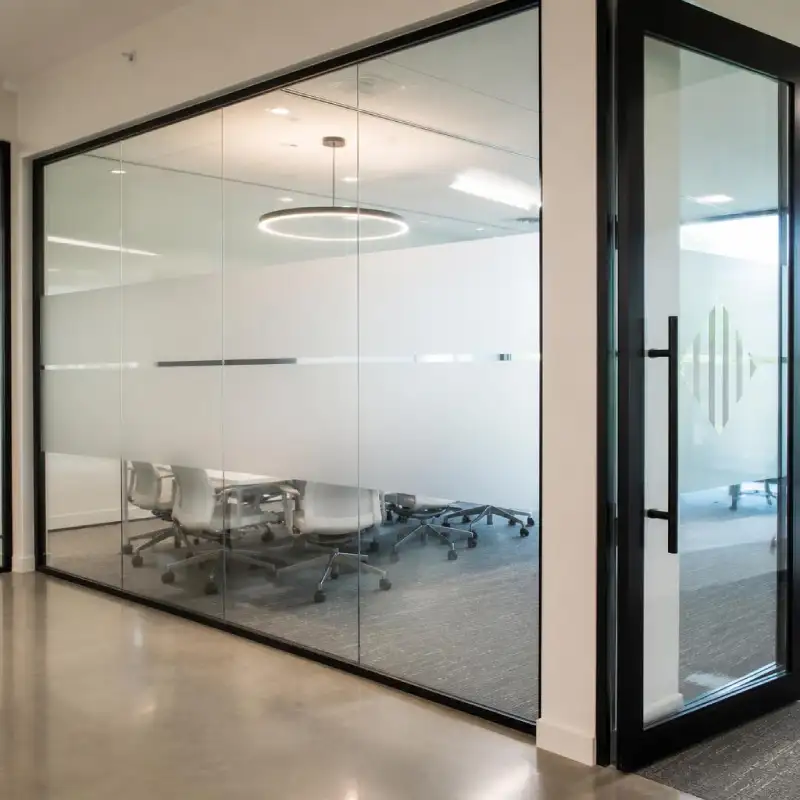 Frosted privacy film and cut-vinyl logo installed on modern office glass walls.