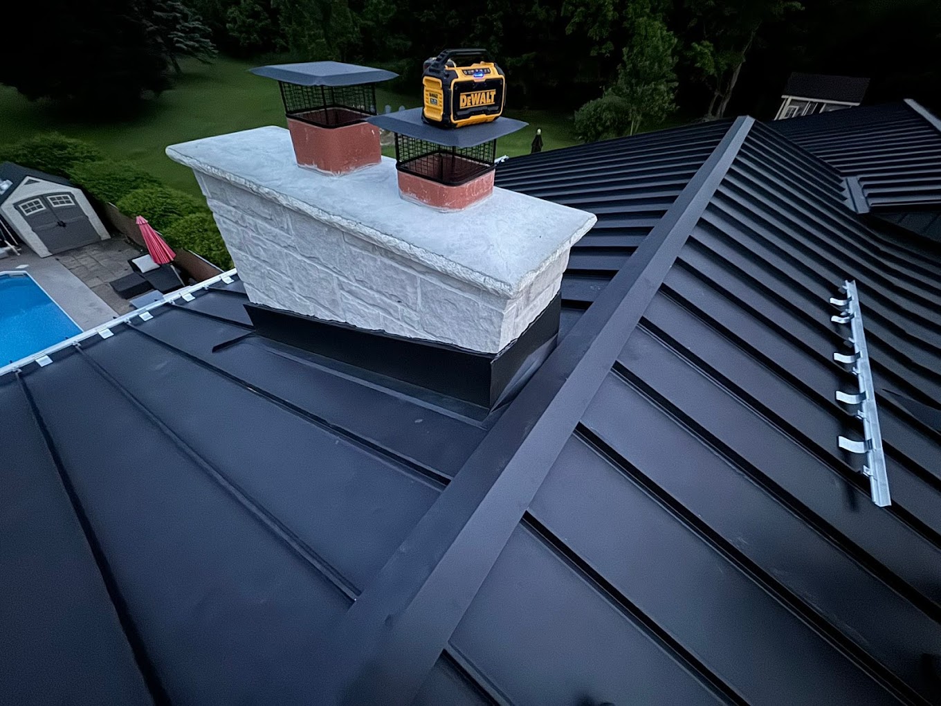Black standing seam metal roof with chimney flashing, snow guards, and custom ridge detailing installed by Infinity Gutters roofing specialists in Ontario