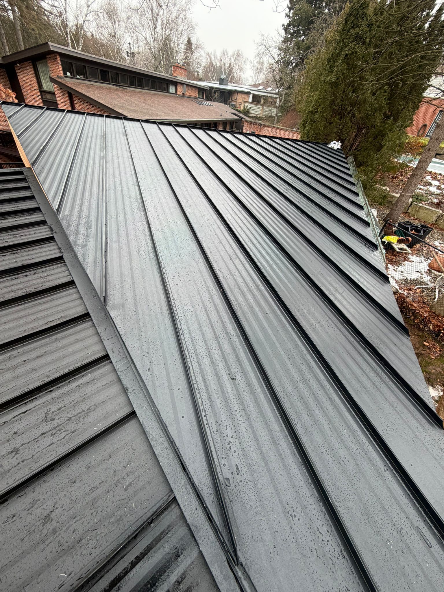 Black standing seam steel roof on a modern Hamilton-area home