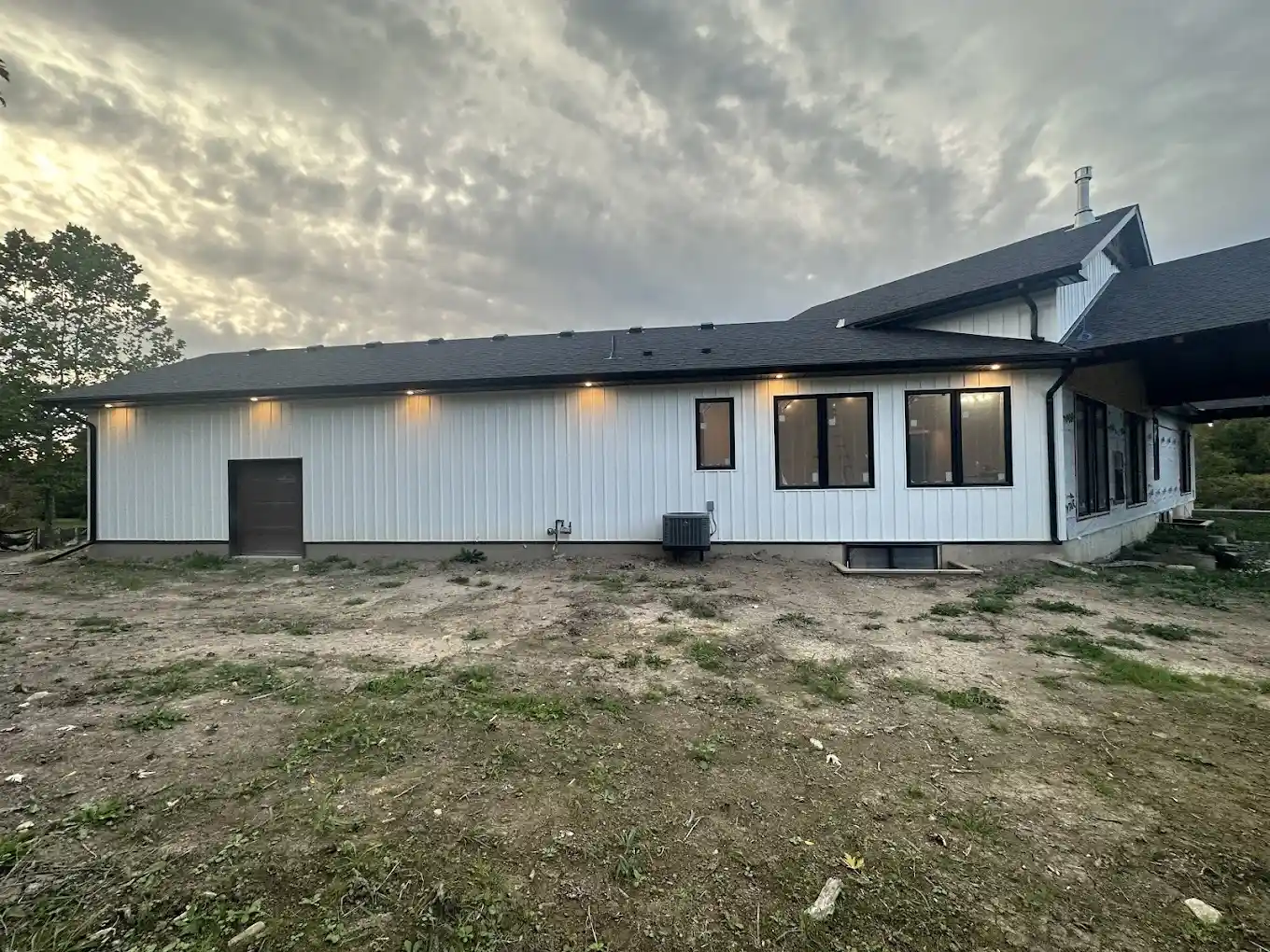 Custom bungalow exterior with seamless gutter installation and modern lighting