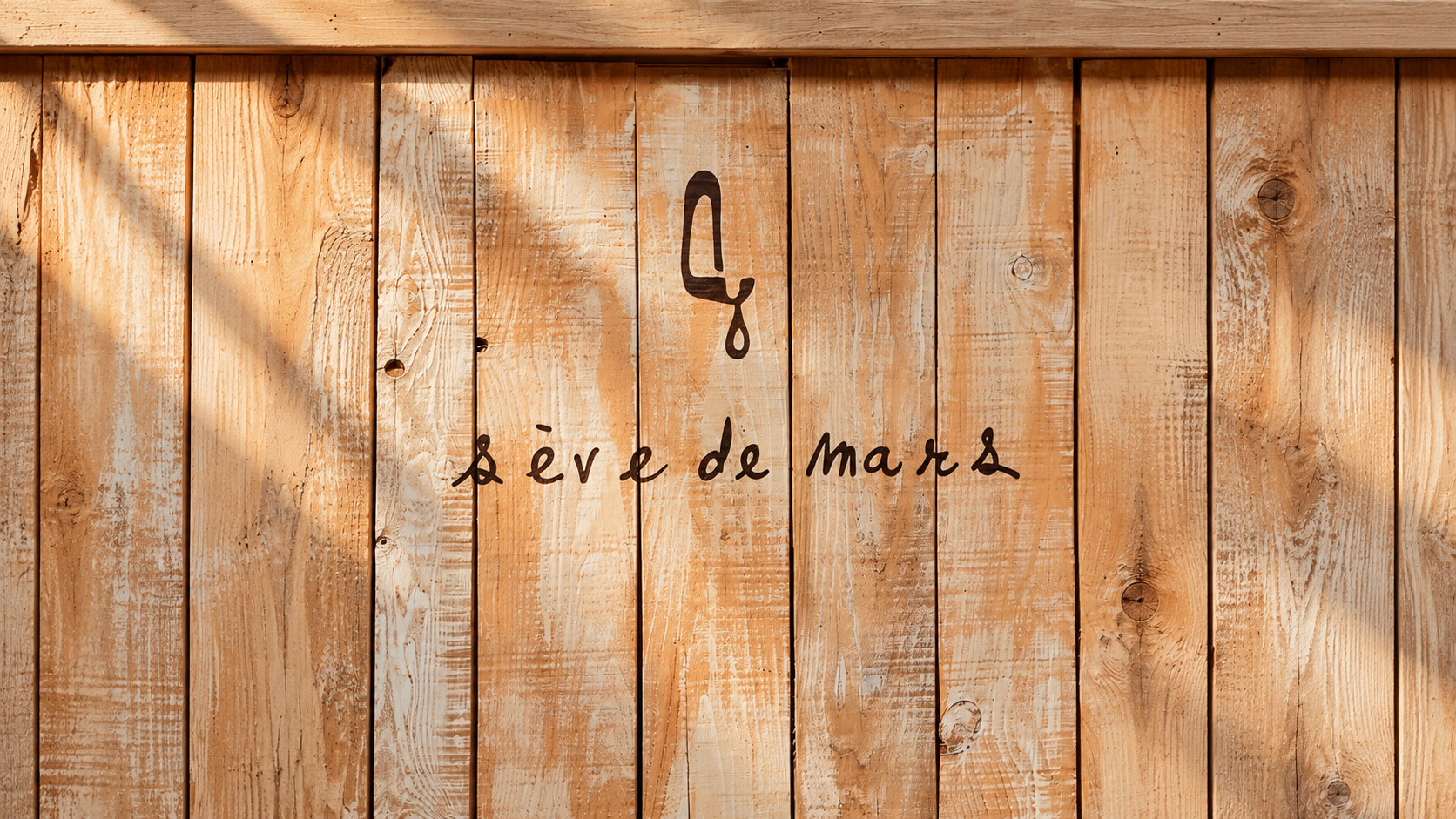Mur de planches de bois clair portant le logo peint Sève de Mars