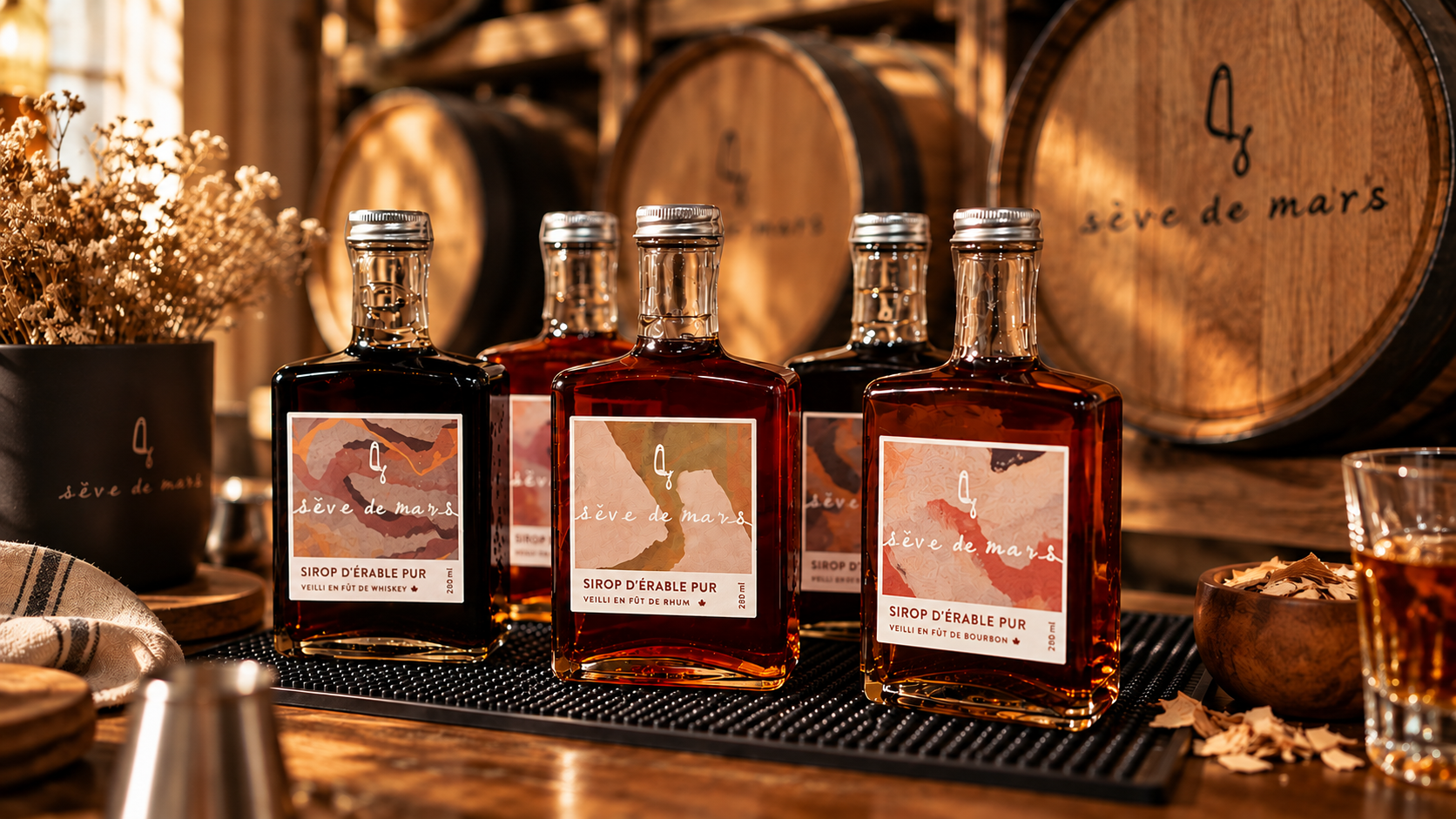 Les bouteilles Sève de Mars — Whiskey, Rhum et Bourbon — alignées devant des fûts de chêne