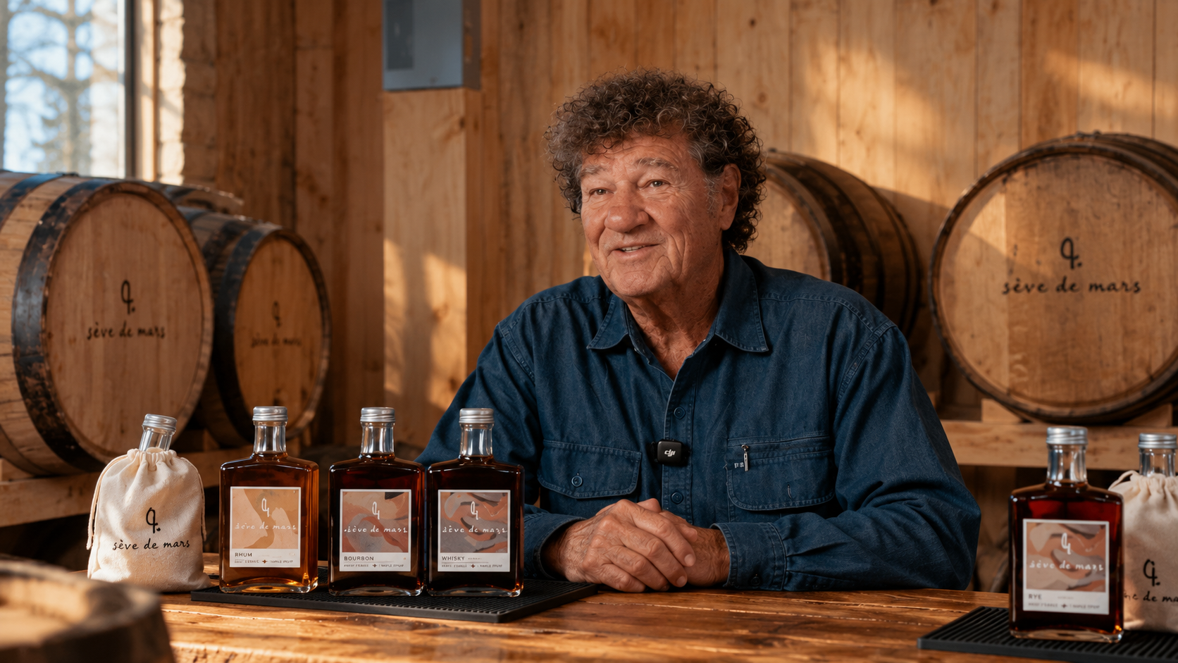 Robert Charlebois attablé au chai devant les bouteilles Sève de Mars