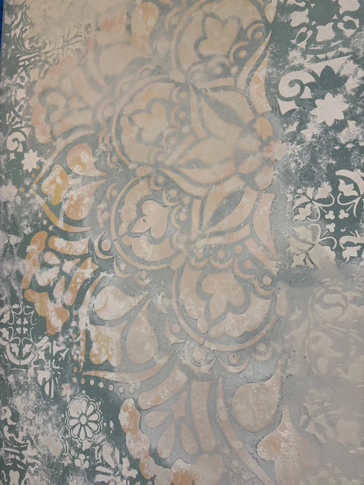Layered decorative plaster finish with floral pattern, soft metallic tones and handcrafted texture
