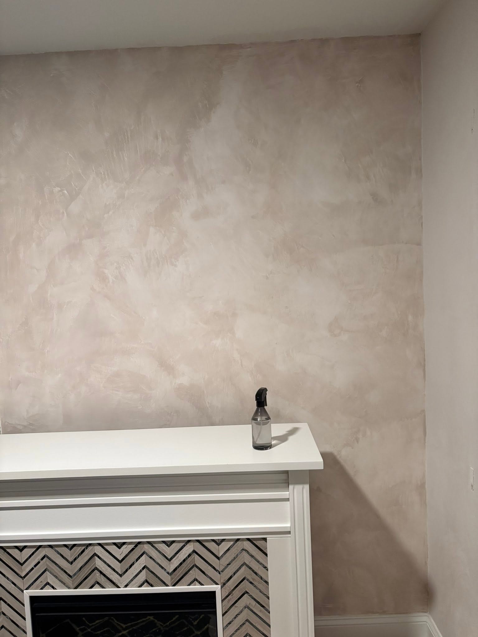 Warm neutral Venetian plaster fireplace feature wall with handcrafted movement and subtle texture