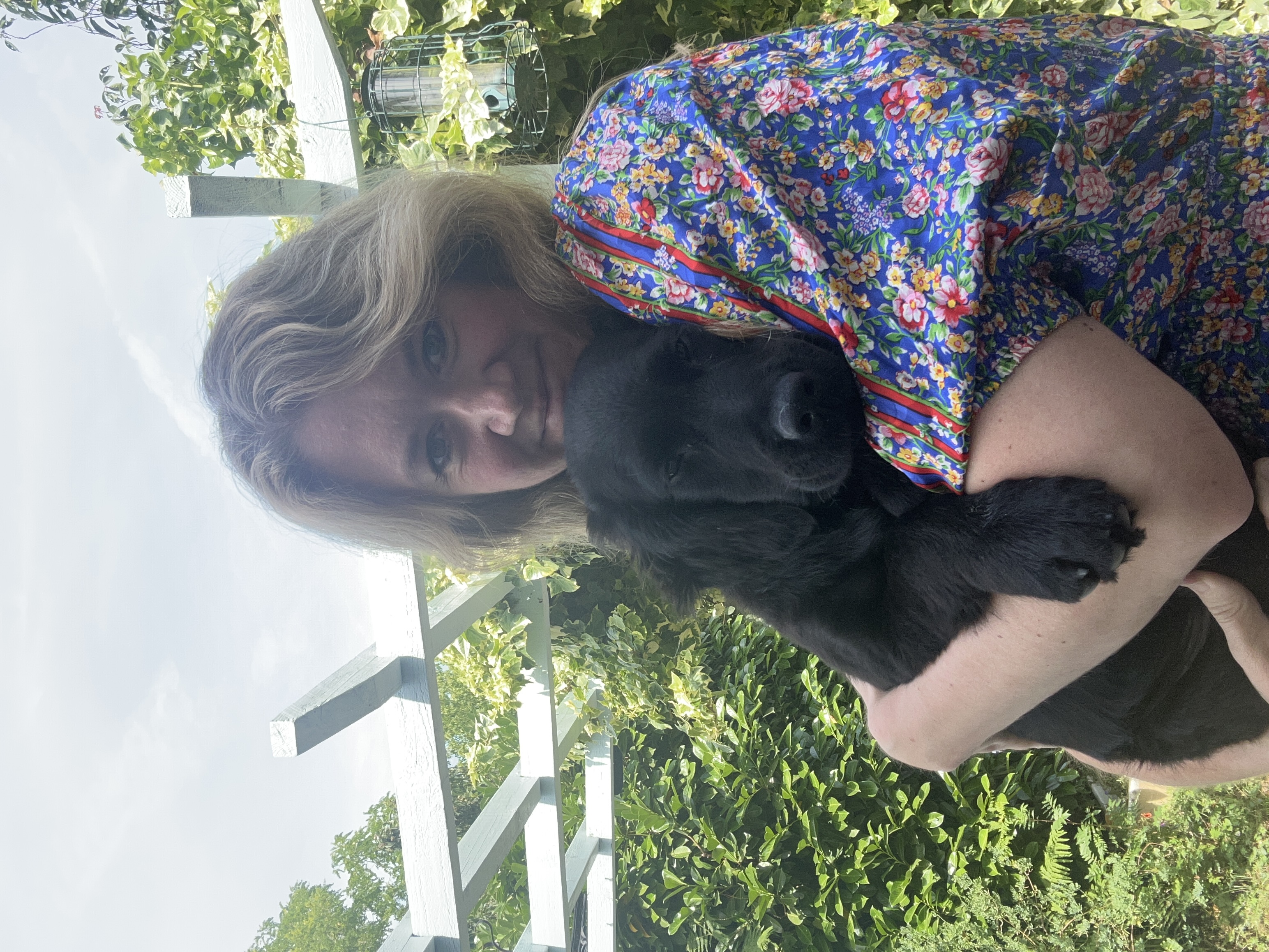 Dog behaviourist Louise Glazebrook holding a black puppy in her garden
