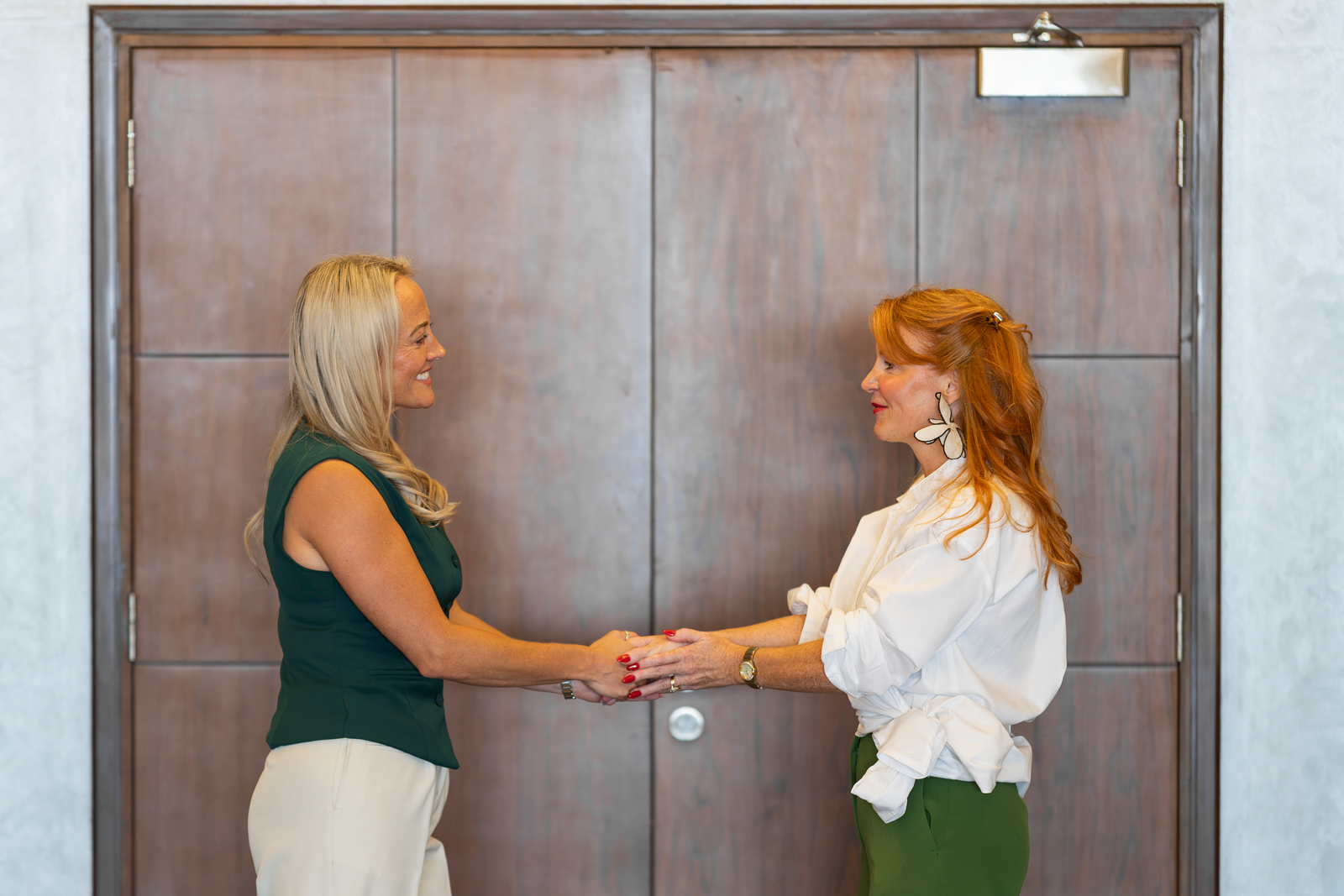 Two women shaking hands at a doorway, representing the written employment contract