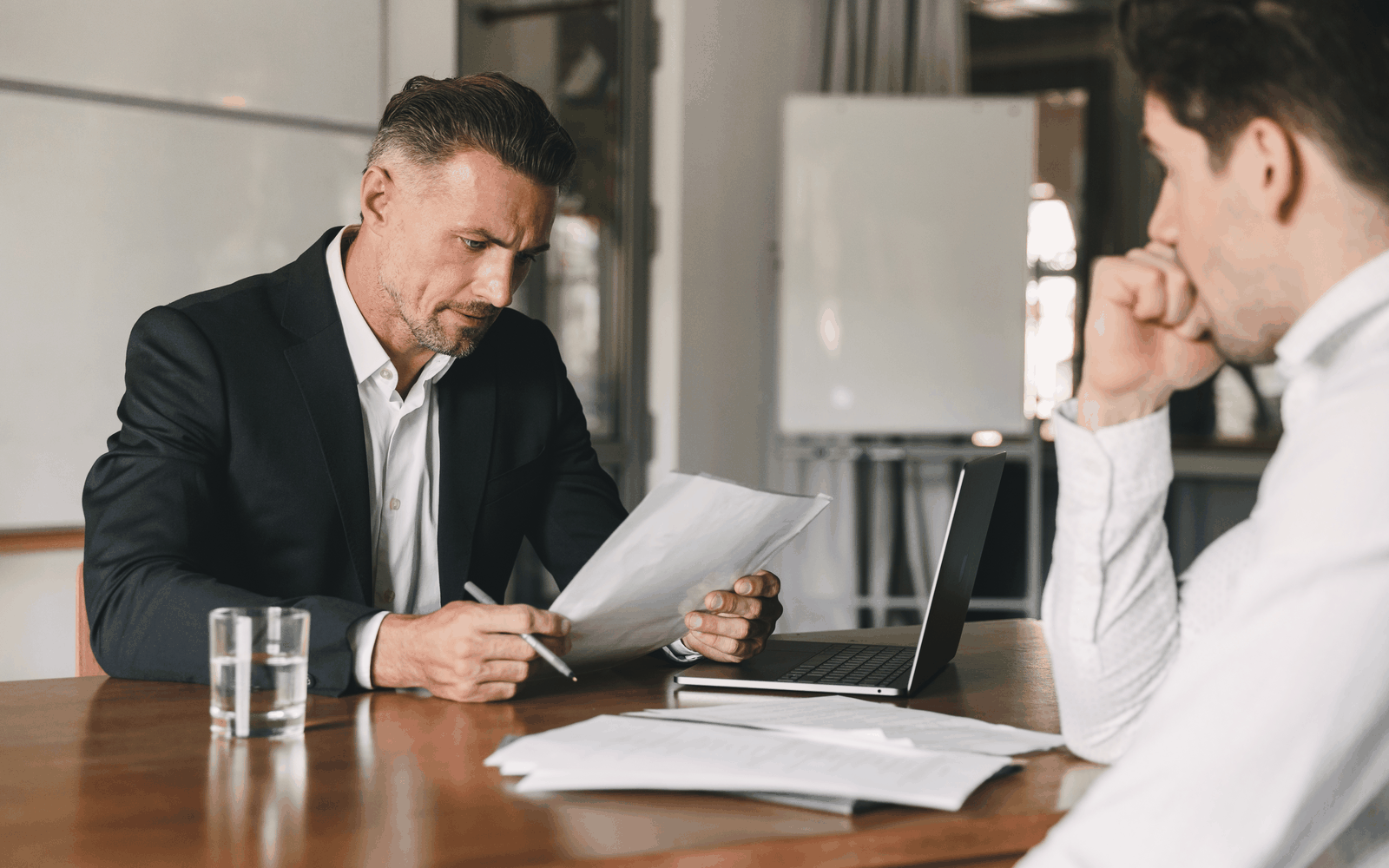 Two men reviewing pension paperwork at a desk in an office