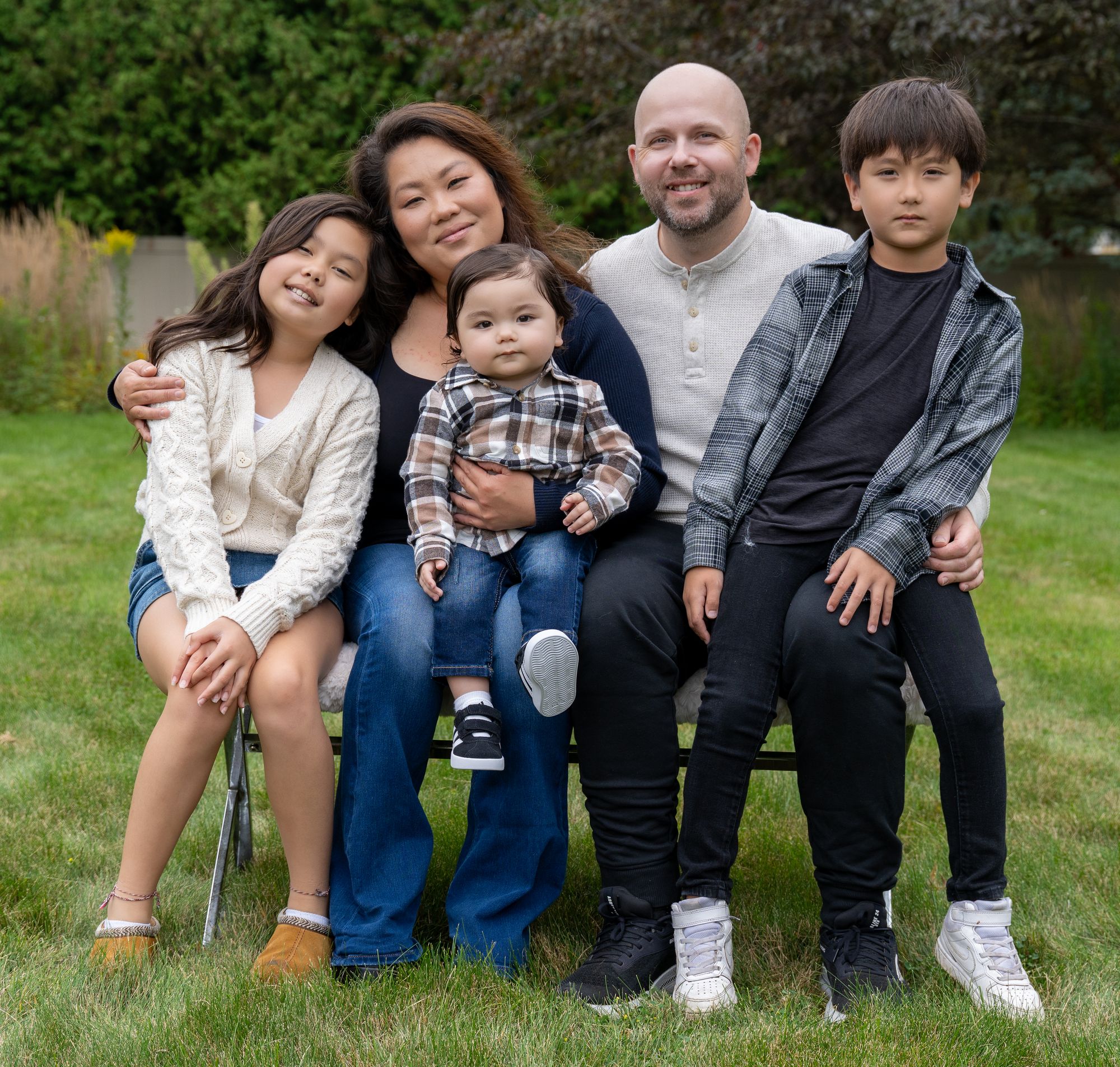 A family of five posing together on the grass