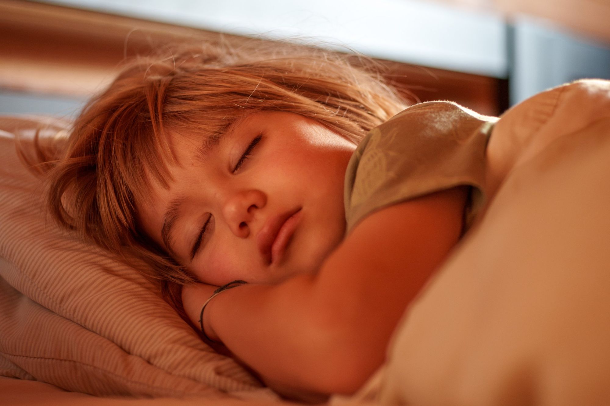 A young boy sleeping in warm morning light