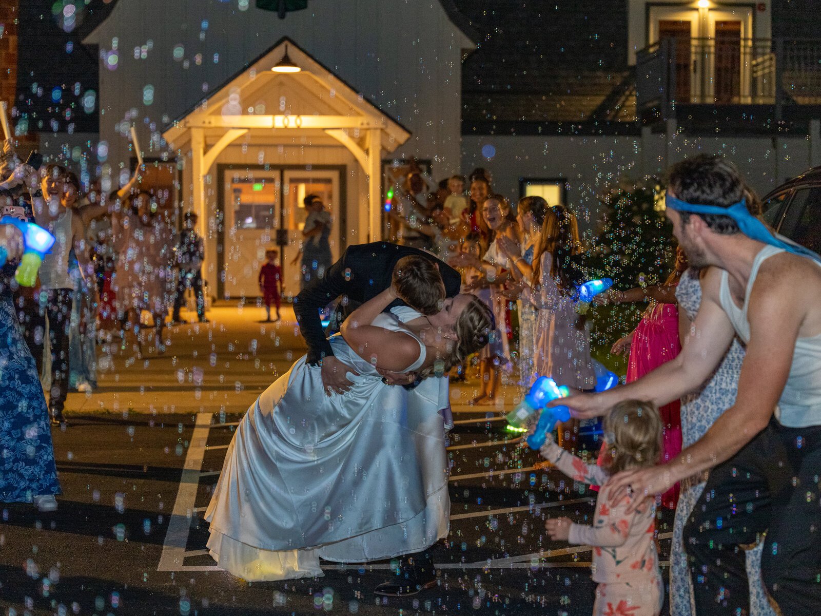 A couple sharing a dip kiss beneath a bubble exit at night