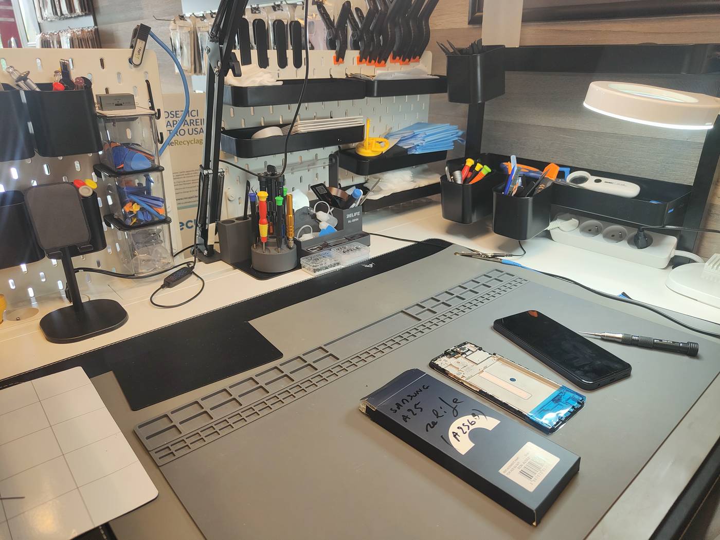Établi de réparation chez Tel&Com à Beaumont, tapis antistatique, tournevis de précision et smartphone ouvert