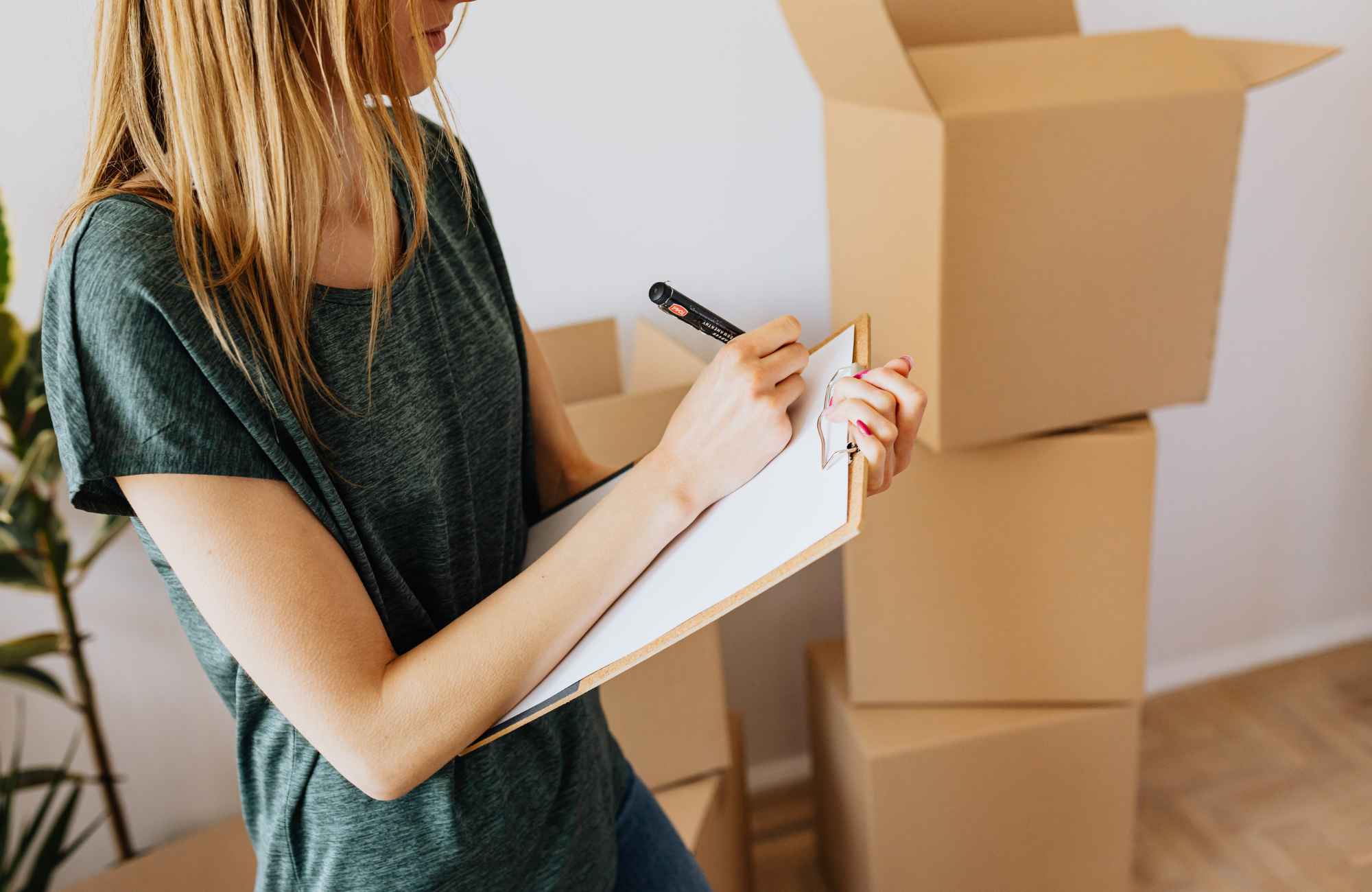 professional-home-organizer-kingman-az-home-organizing-before-a-move-woman-writing-on-a-clipboard-with-moving-boxes-peaceful