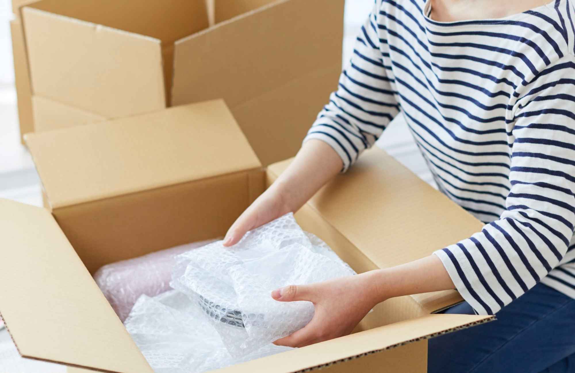 move-management-prescott-az-home-organizing-before-a-move-woman-packing-fragile-bubble-wrapped-plates-in-moving-box-simple
