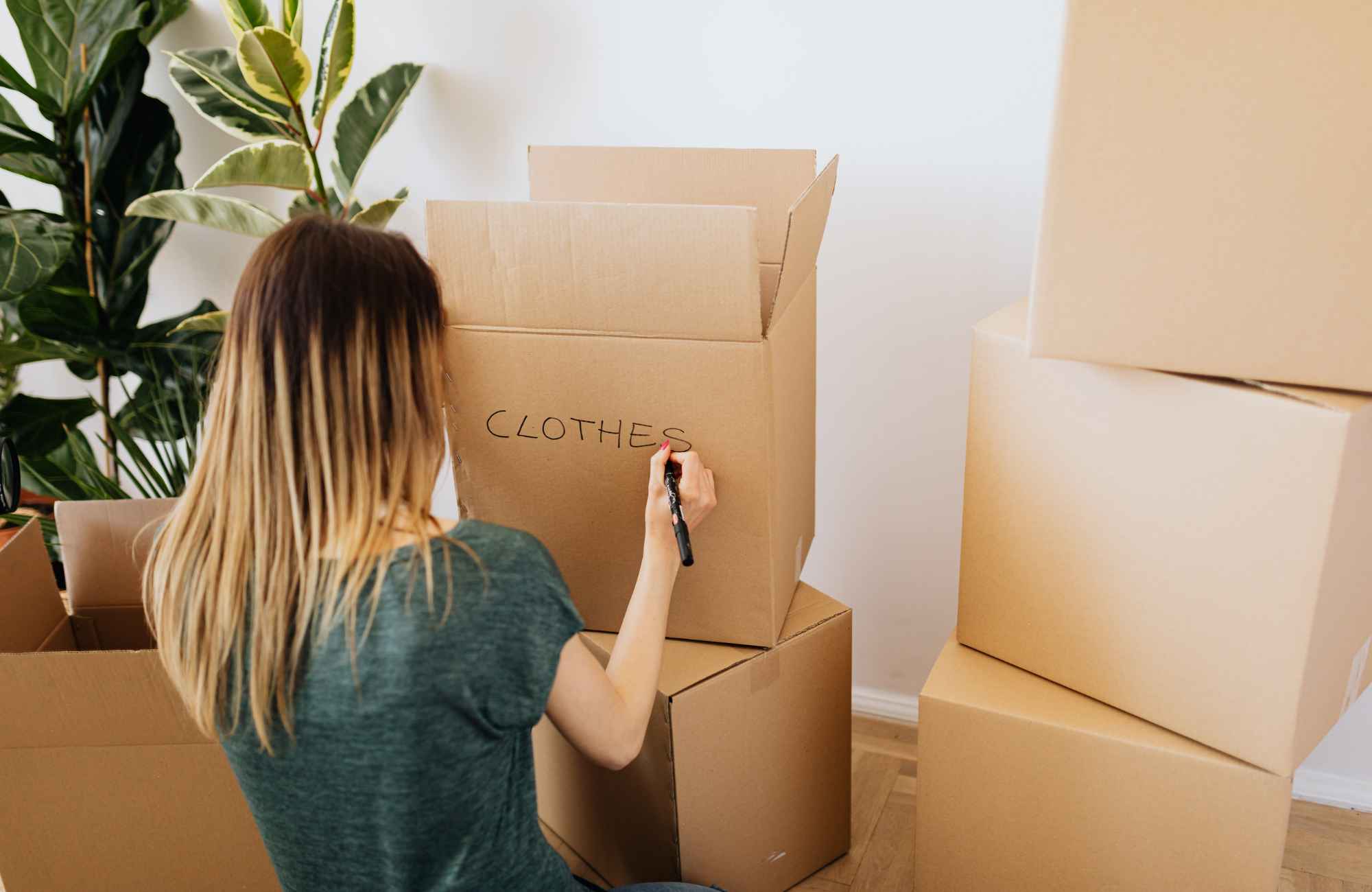 professional-home-organizer-sedona-az-preparing-for-a-move-woman-labeling-moving-boxes-stacked-practical-systems-move-management