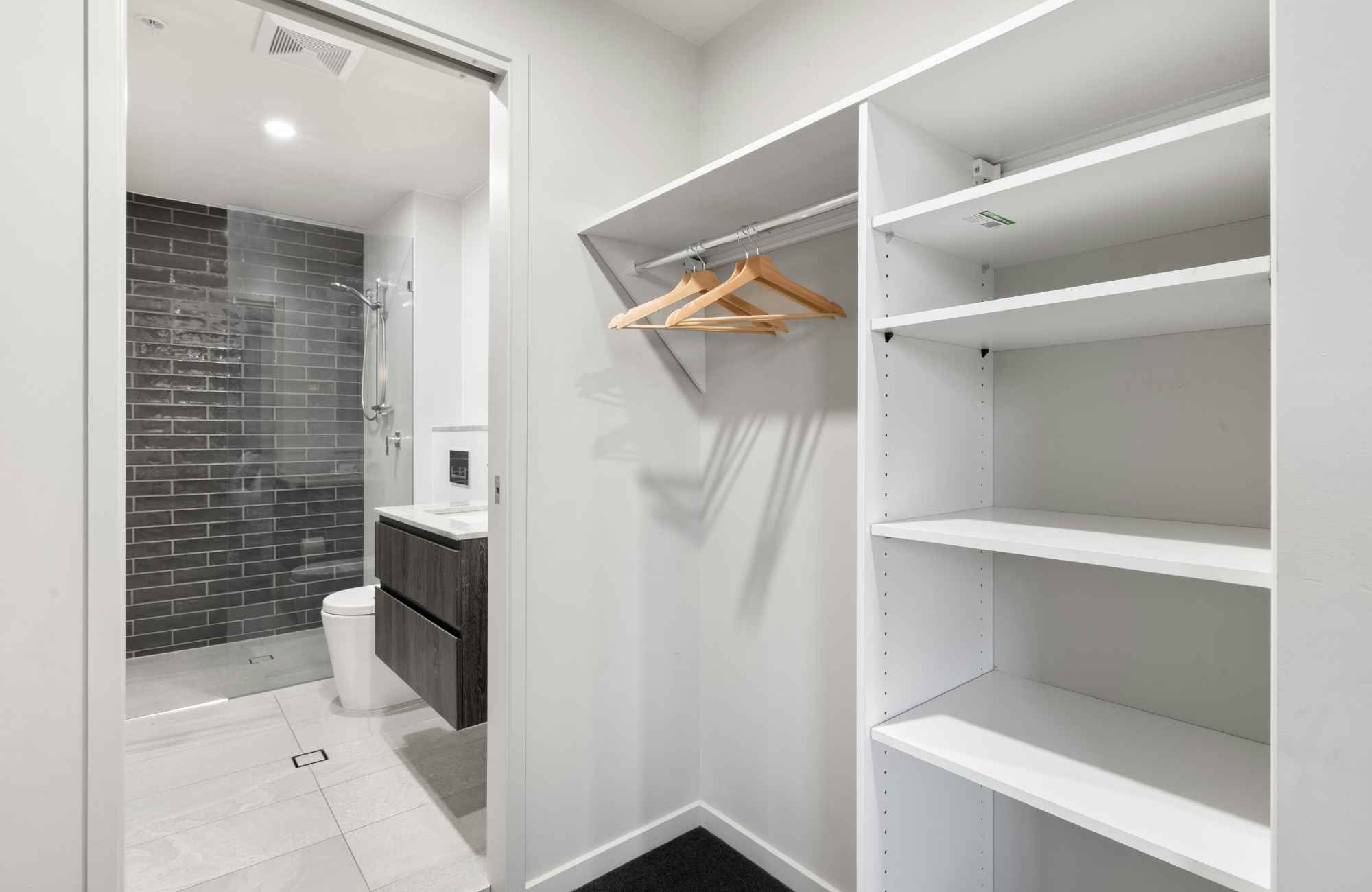 shannon's-organizing-solutions-kingman-az-settled-after-move-walk-through-closet-with-built-in-shelves-bathroom-with-dark-tile-shower shannon's-organizing-solutions-kingman-az-settled-after-move-walk-through-closet-with-built-in-shelves-bathroom-with-dark-tile-shower