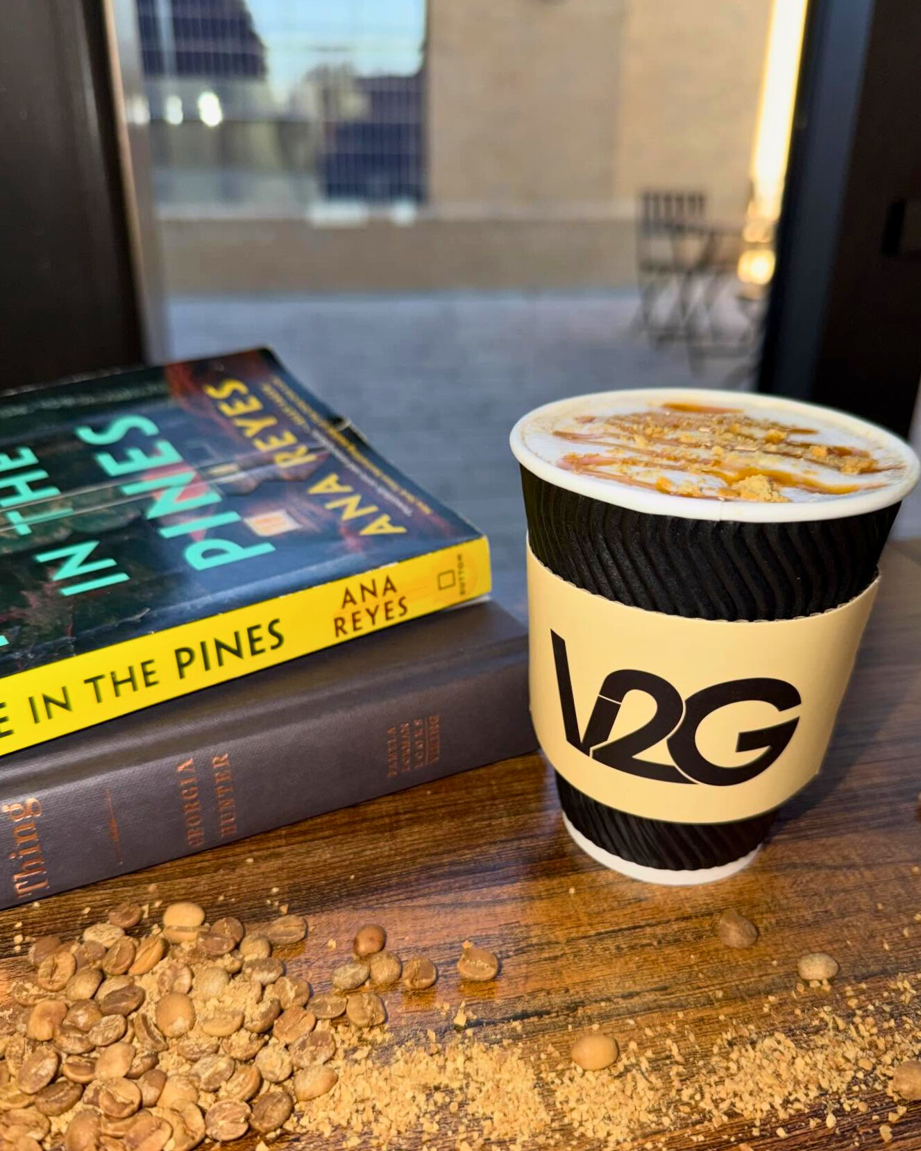 White coffee from Vibes 2 Go served in a branded cup on a table with books and coffee beans inside Midland Community Theatre