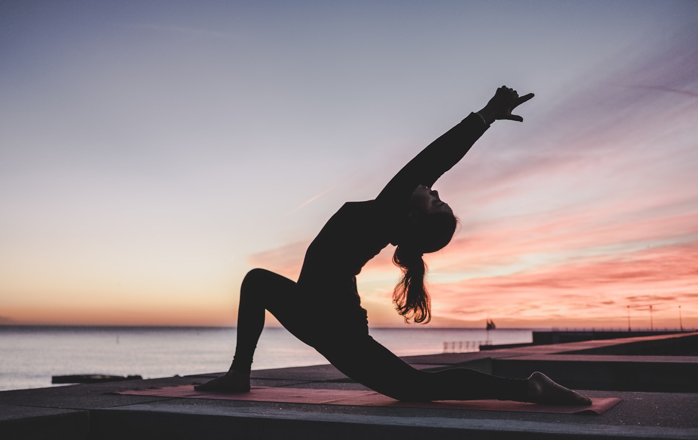 Yoga-Silhouette bei Sonnenuntergang – Betriebliches Gesundheitsmanagement für ausgeglichene Mitarbeiter