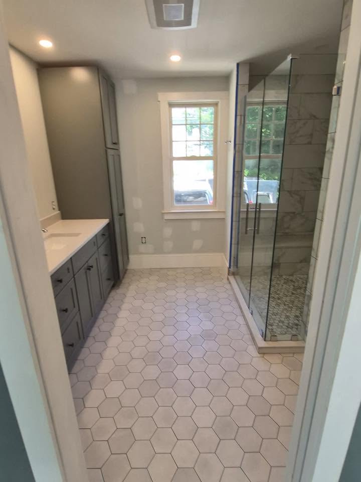 Finished bathroom remodel with walk-in shower, vanity, tile, and warm lighting