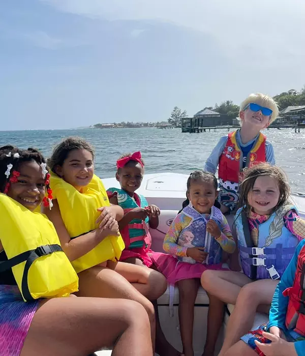 6 happy kids on a boat with life jackets on