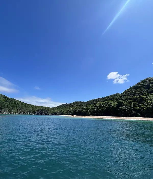 a beach in the caribbeanon a sunny day with mountains in background