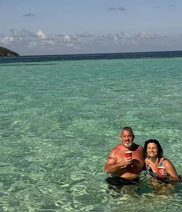 woman and man in clear water holding red cups