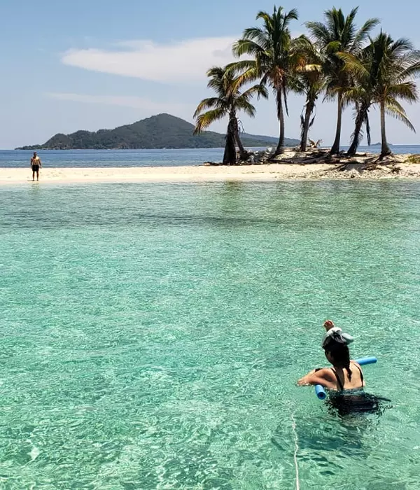 man on an isolated island and woman on a noodle in clear water