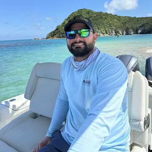 man with beard on a boat and the caribbean in the bacground