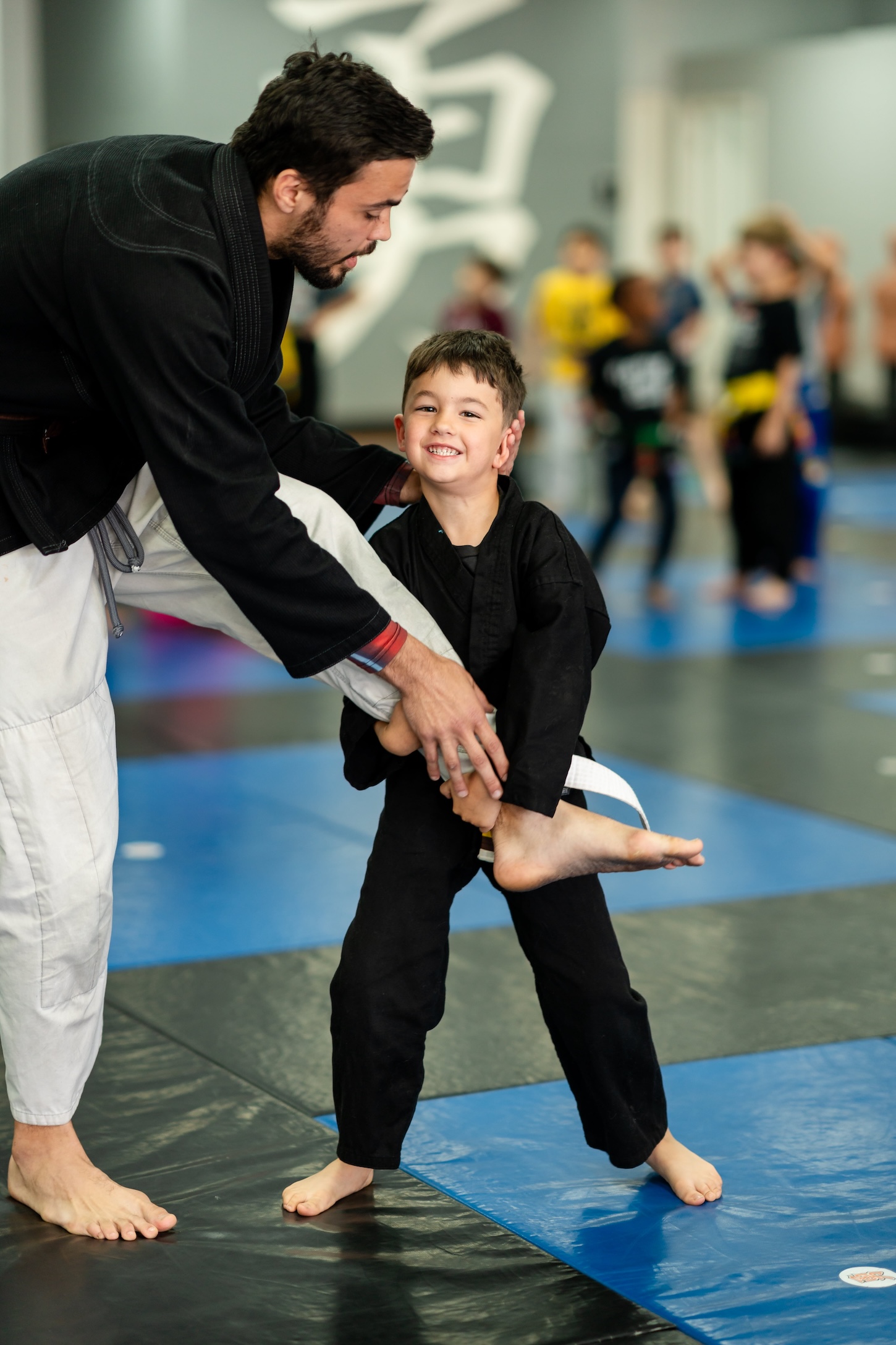 Kids Jiu Jitsu class in Fresno, coach guiding a young student through a technique at Ultimate Martial Arts