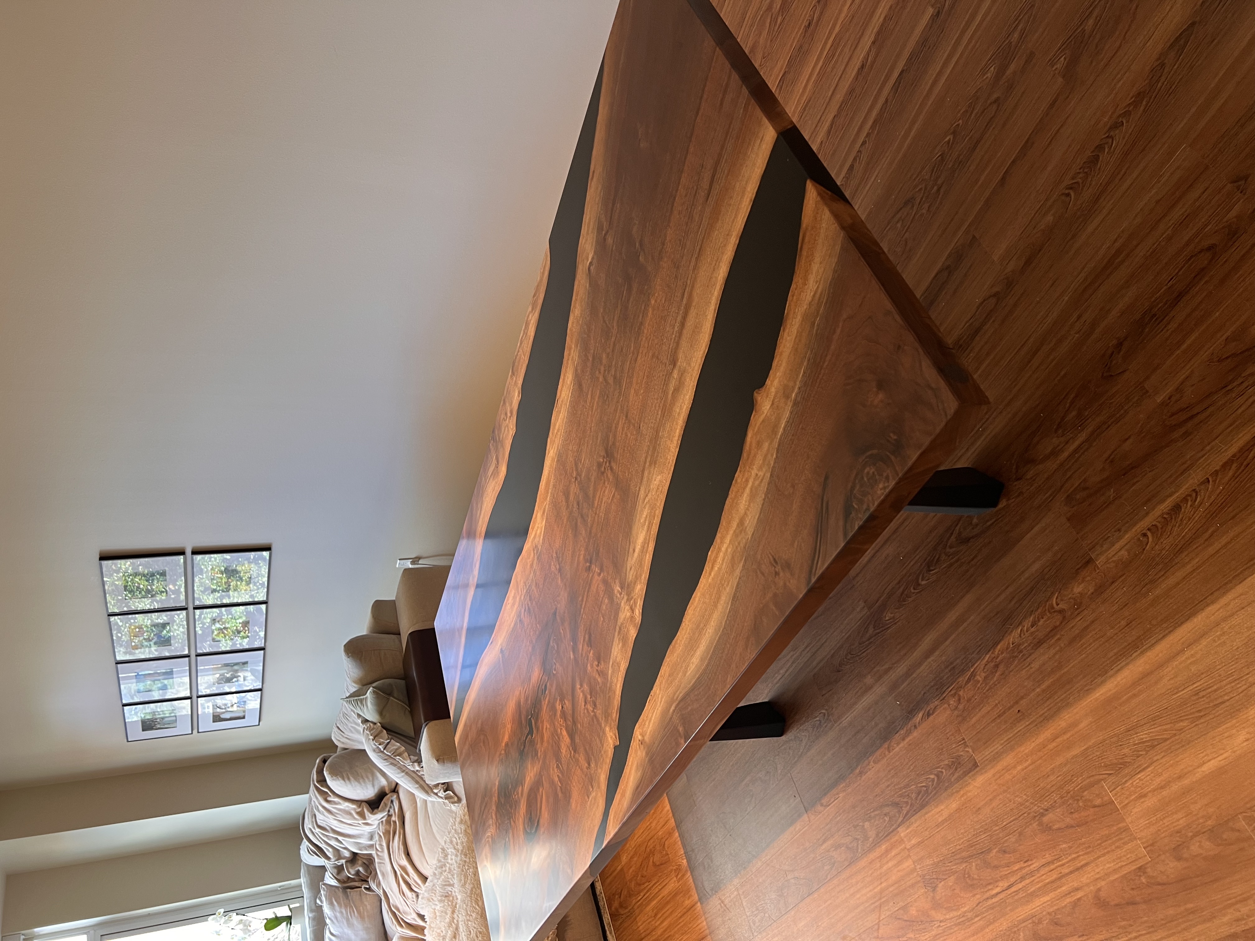 A handcrafted live-edge dining table with a black epoxy resin river inlay in a modern living room.
