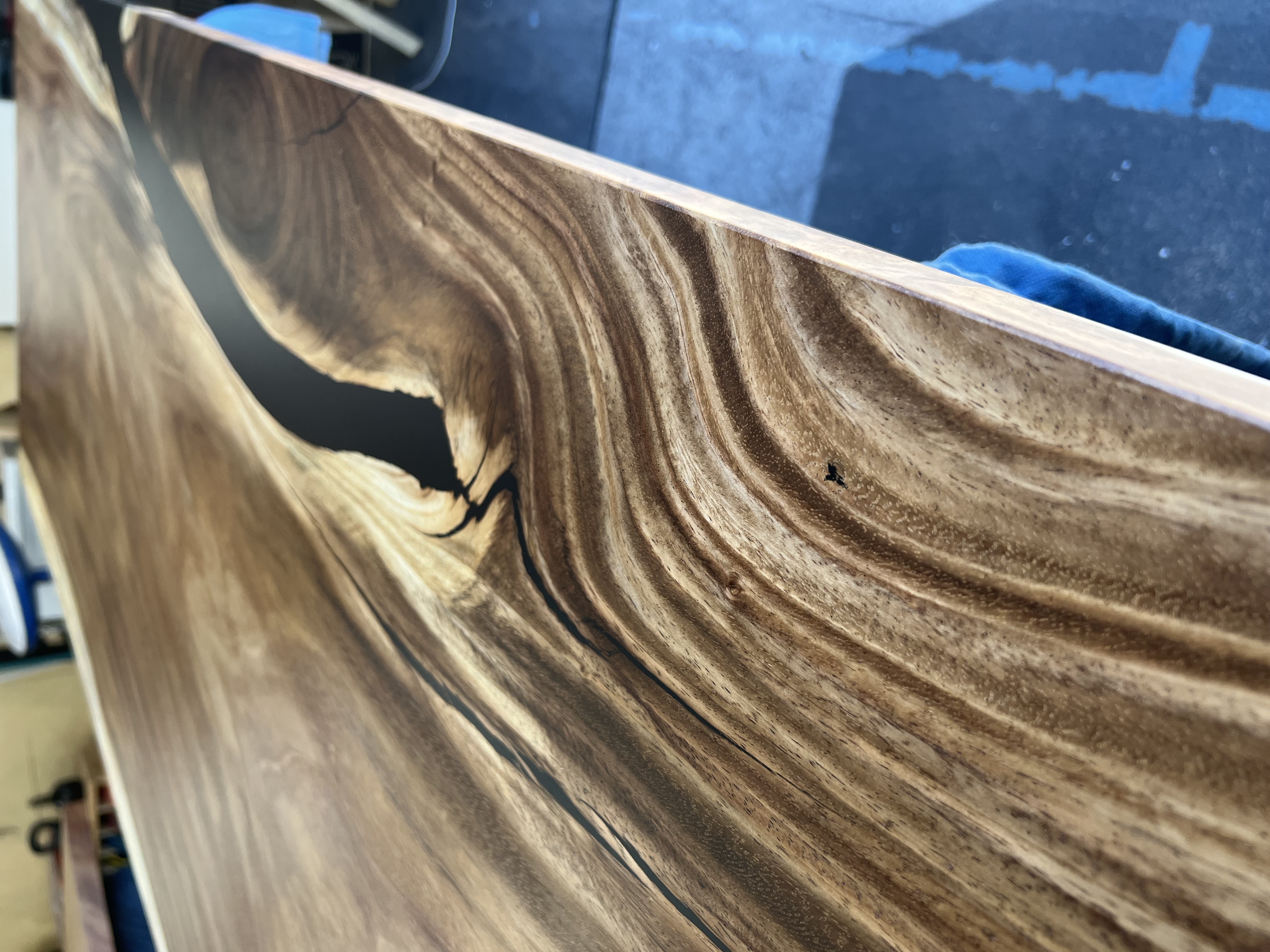 A polished wooden slab with a black epoxy resin river running through a natural void.