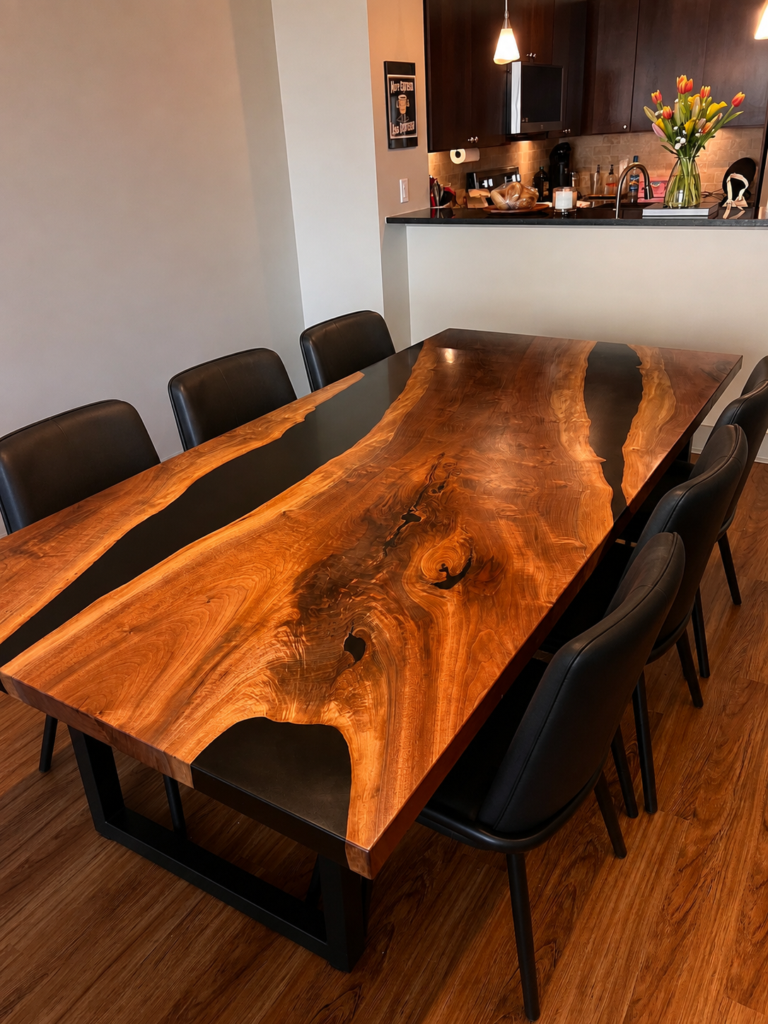 A live-edge dining table joined by black epoxy resin rivers, surrounded by six black chairs.