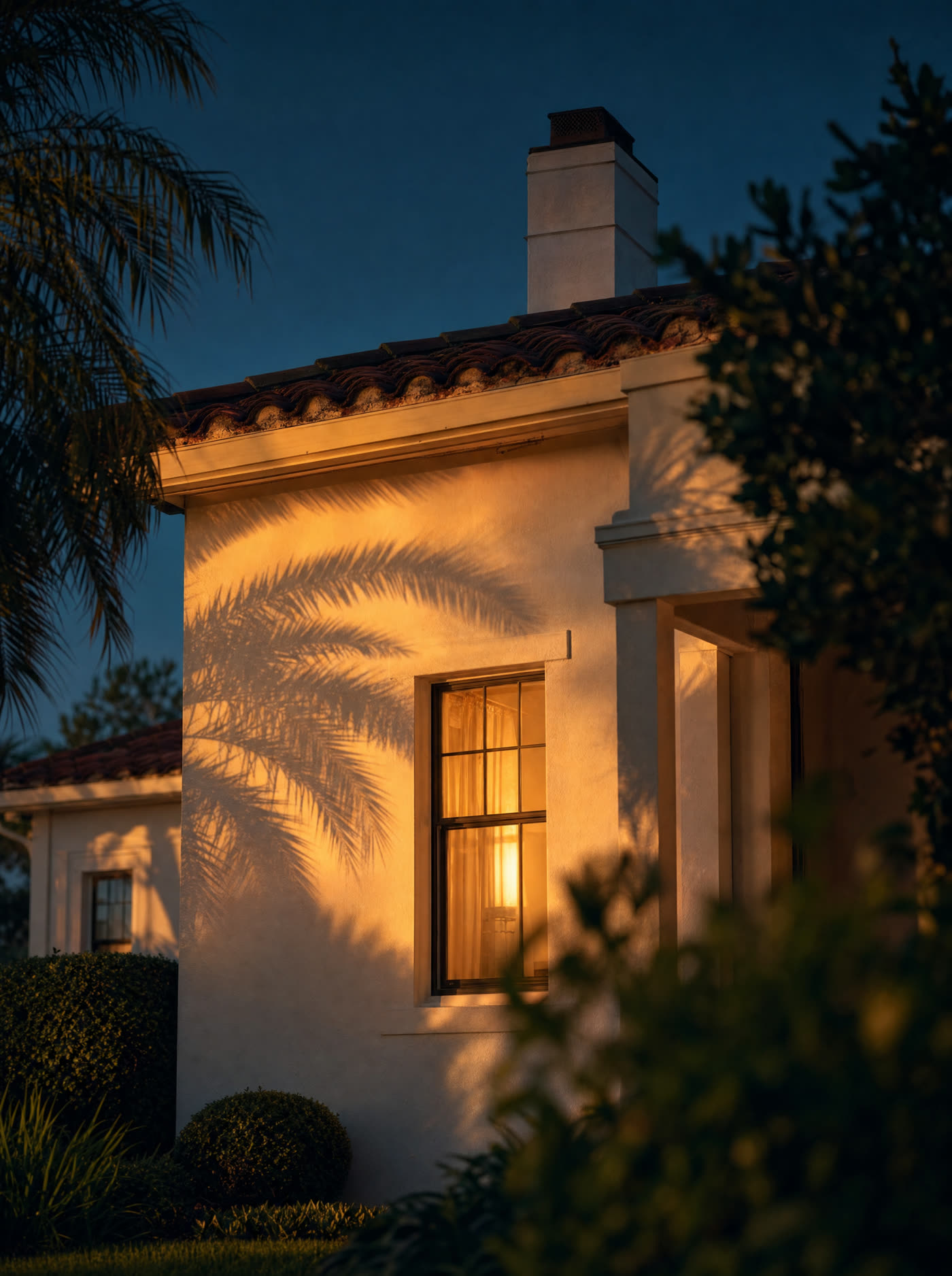 A Florida home at dusk with one window lit warm from inside