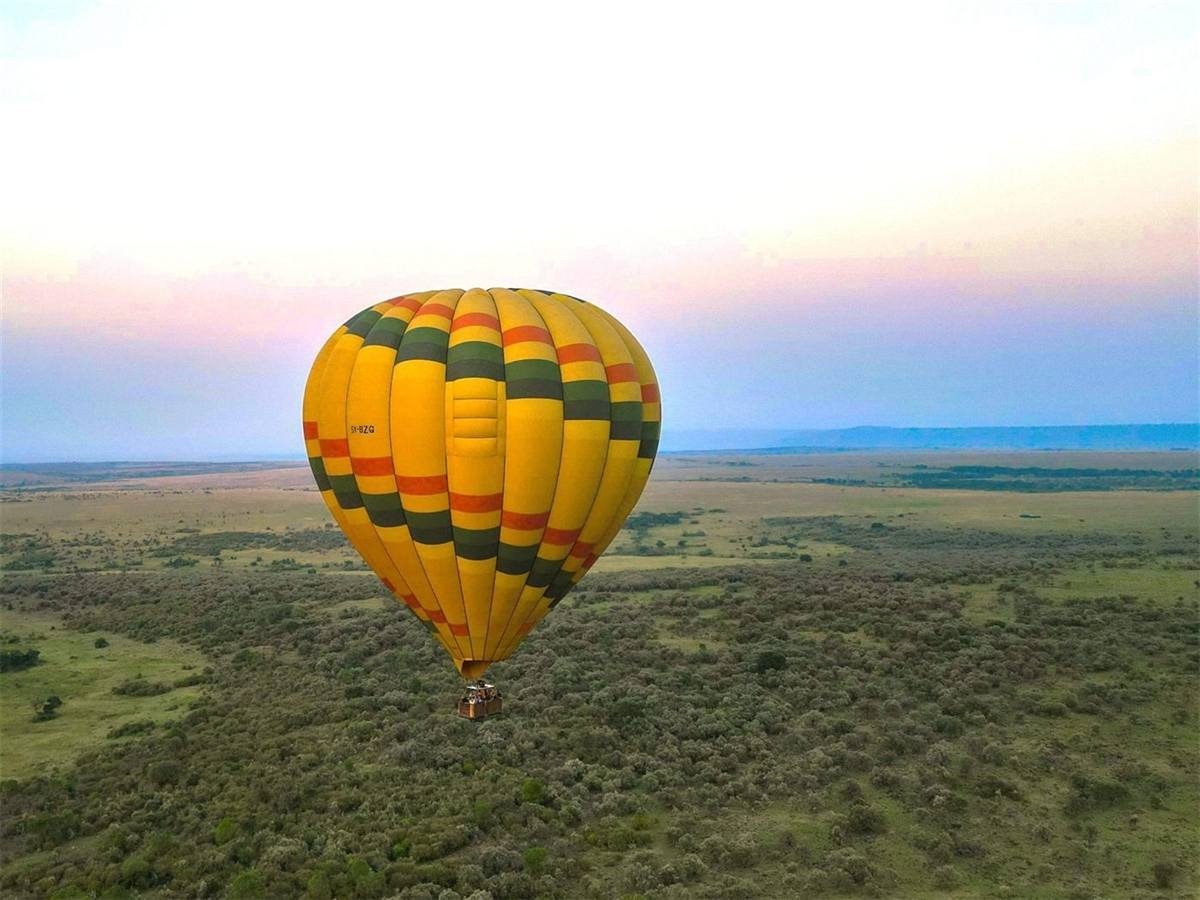 A hot-air balloon lifting off over the Maasai Mara at first light