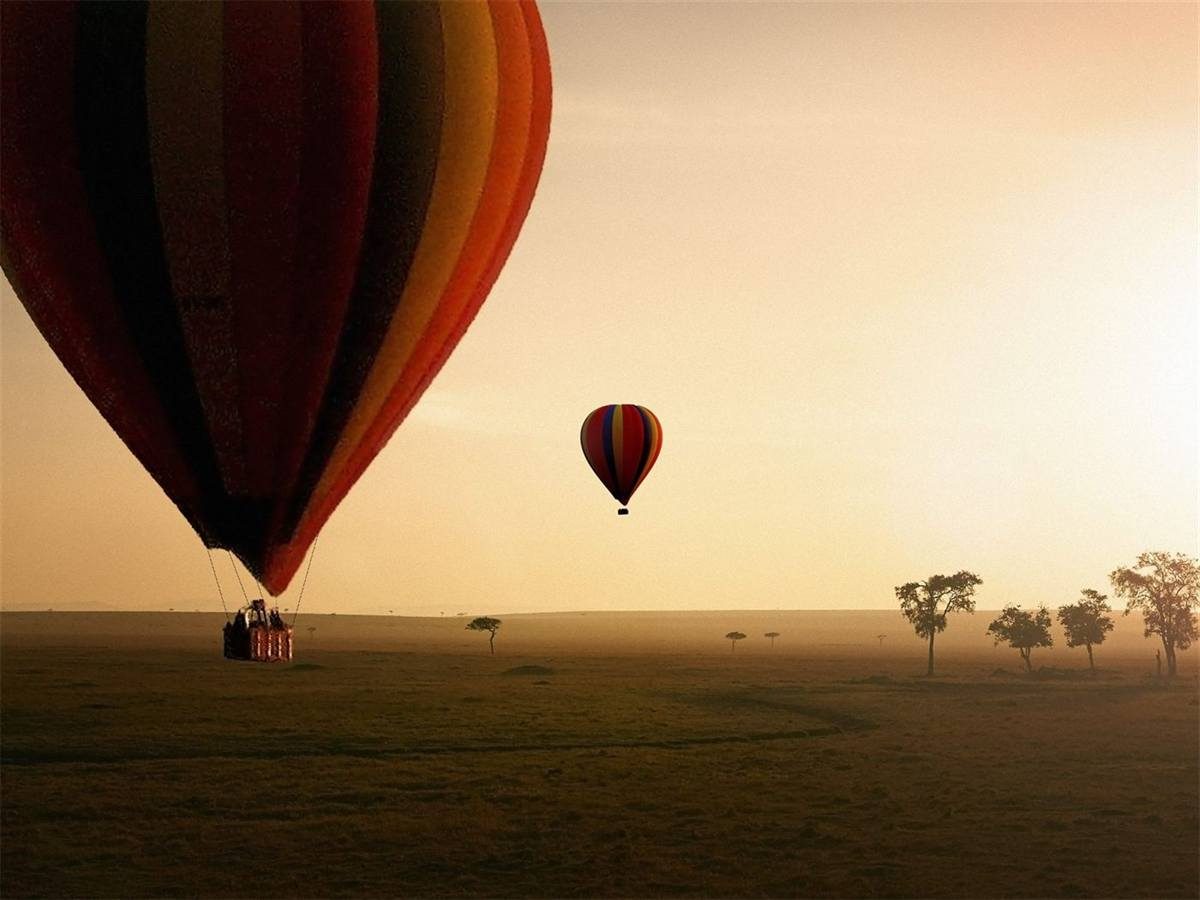 A balloon drifting low over the Serengeti plains at sunrise