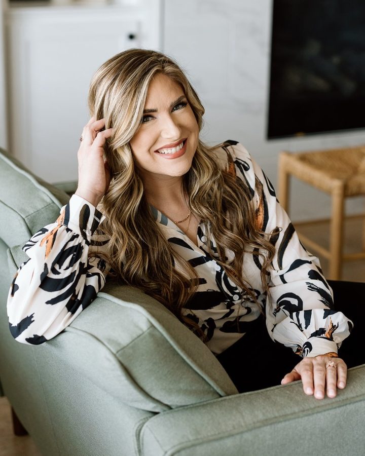 Rachel Rogers smiling on a sage green sofa