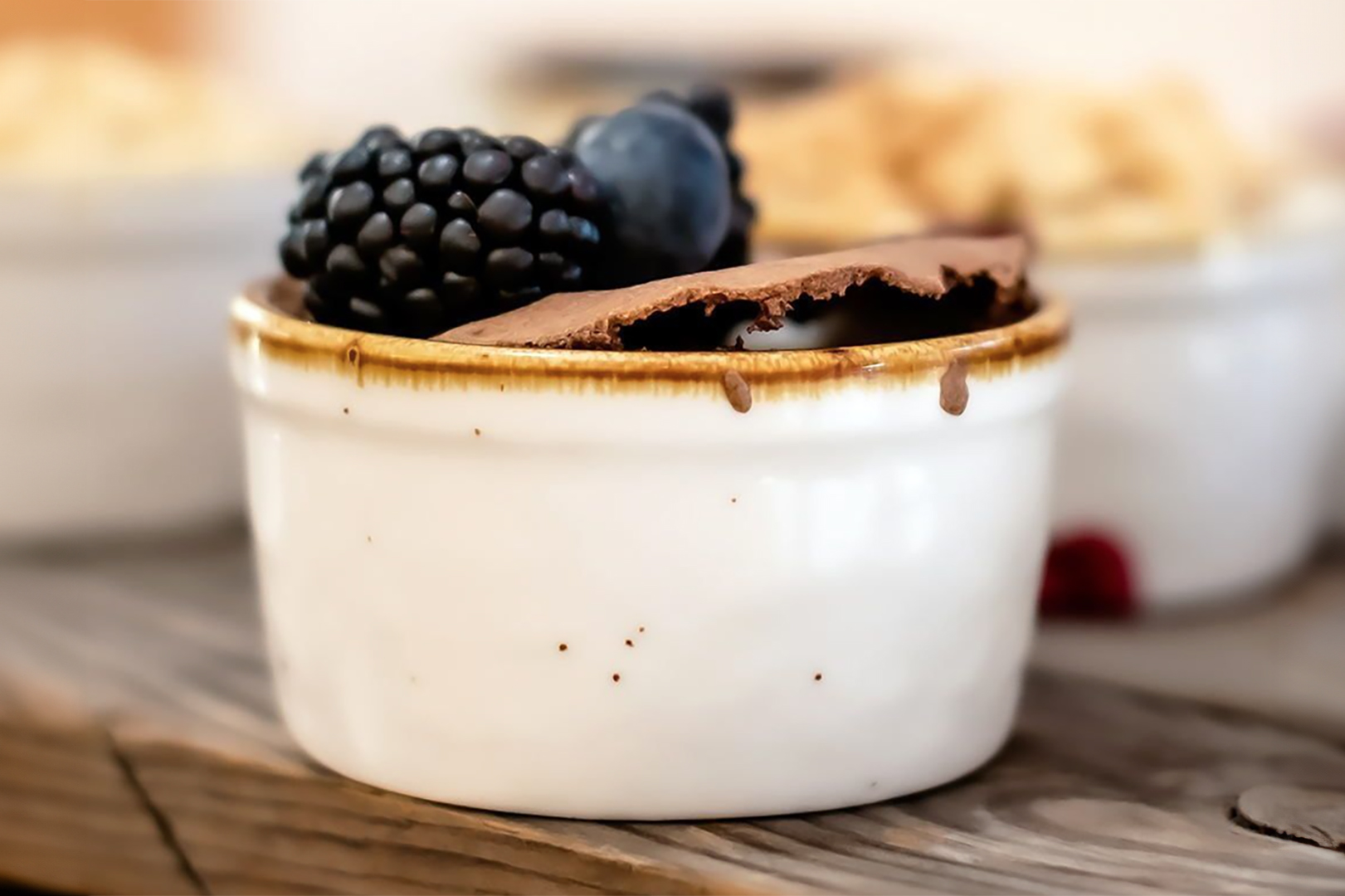 Wedding reception dessert of chocolate mousse with an assortment of blackberries and blueberries in a white clay single serving cup. 