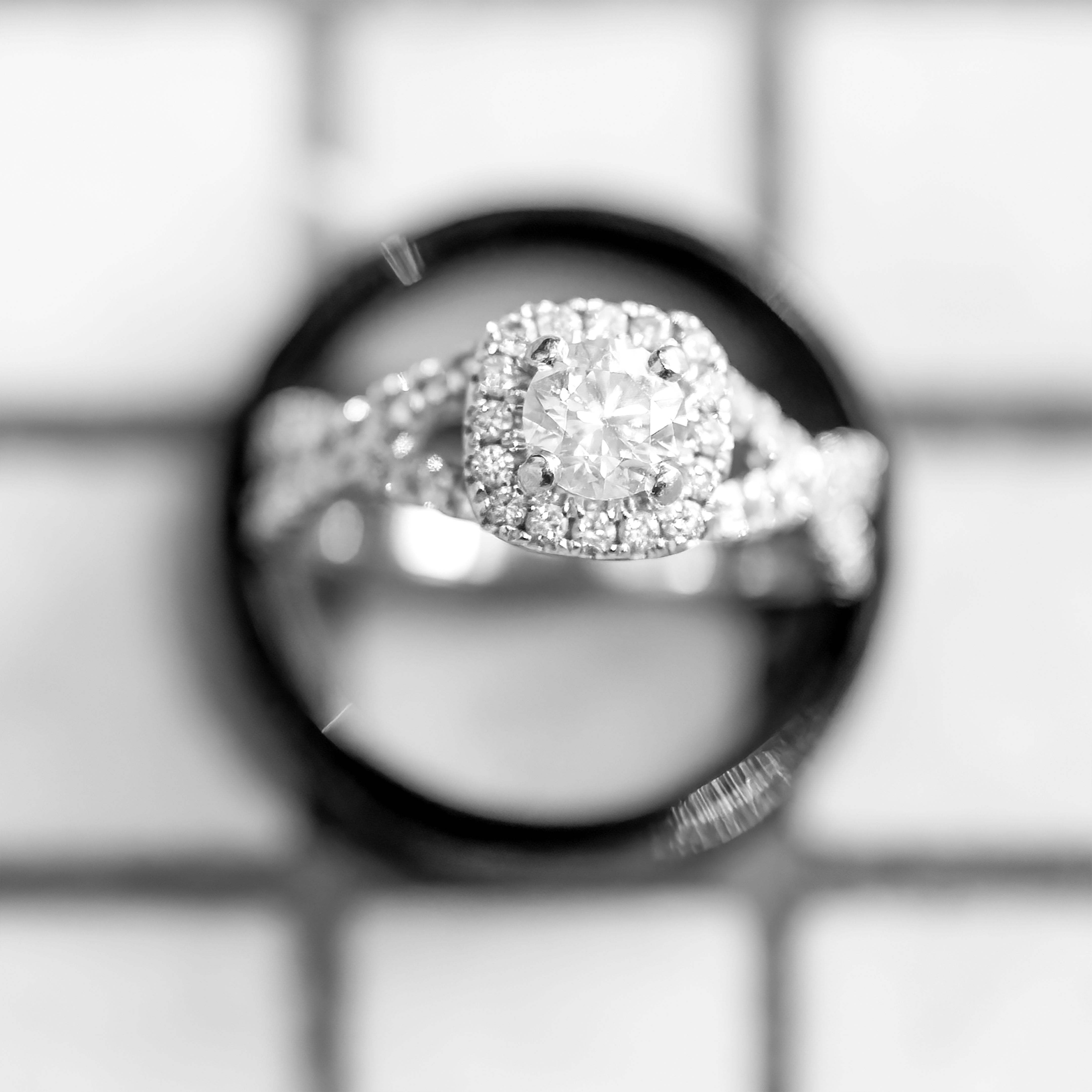 Black and white photo of wedding bands and engagement ring on a white tile counter at Roche Harbor Resort on San Juan Island, WA. 