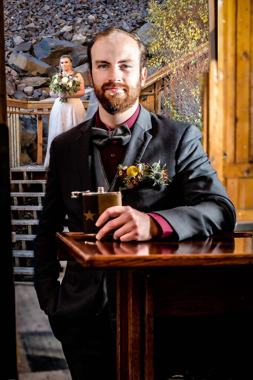 Bride walking down the stairs to surprise her groom for their first look. Groom is holding a flask of whiskey at the bar at Chateau Rive. 